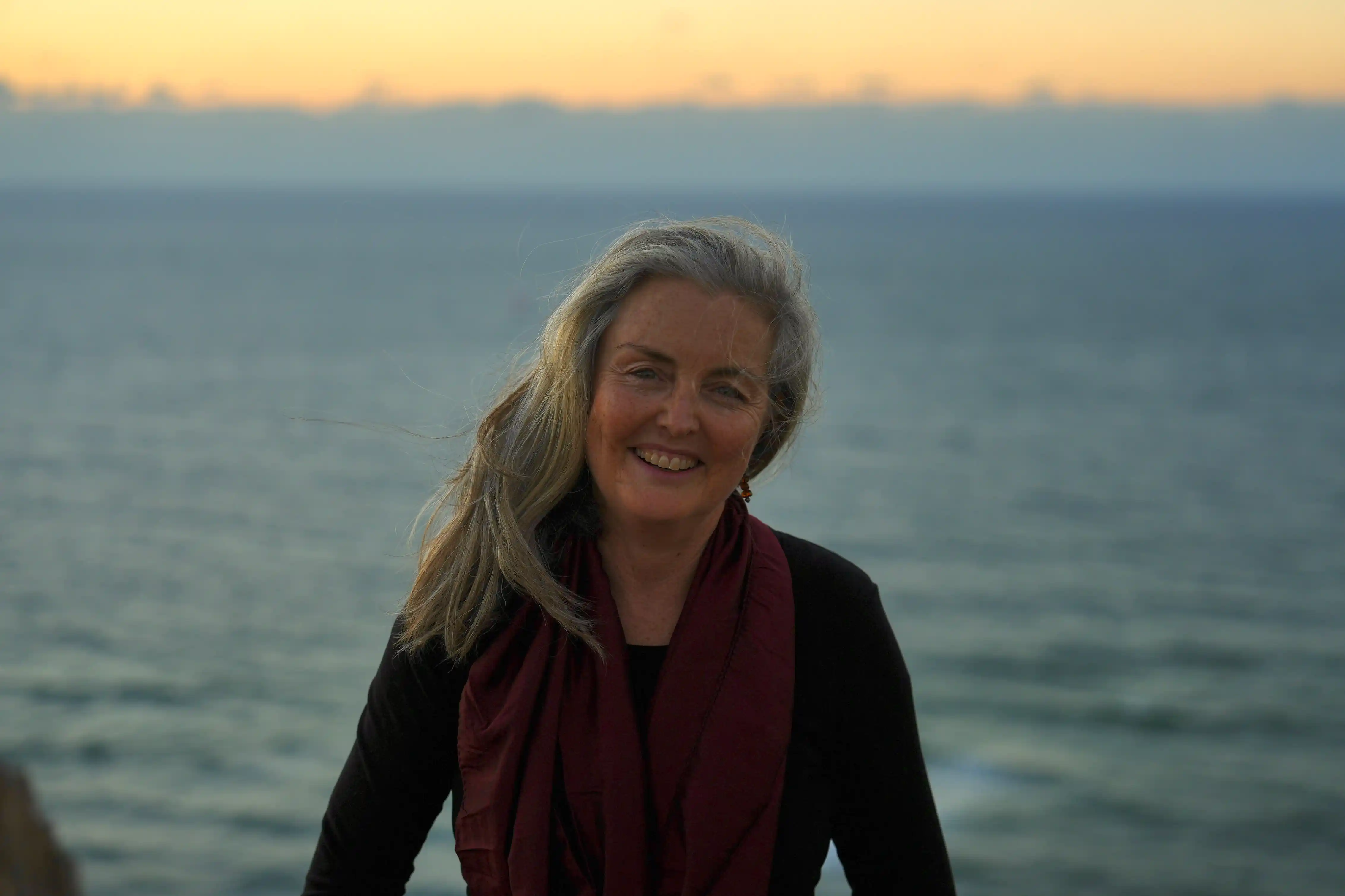 Georgia Marnham at sunset by the ocean with mountains in the background