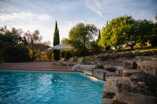 Beautiful swimming pool at Casa Cales in evening light with stone terracing and lush Mediterranean gardens