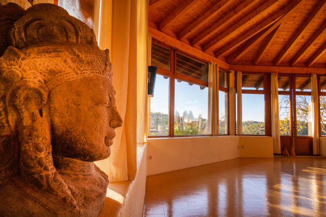 Yoga studio at Casa Cales retreat venue with traditional Buddha statue and panoramic views