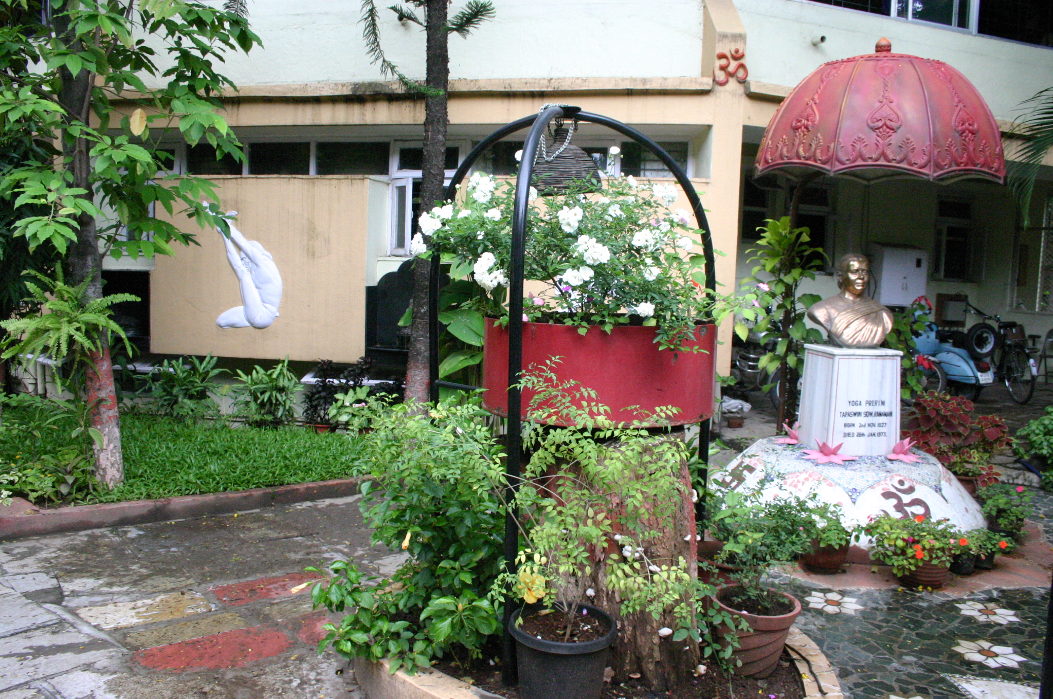 The courtyard of RIMYI (Ramamani Iyengar Memorial Yoga Institute) in Pune, India, showing the peaceful garden with traditional yoga props, a statue of B.K.S. Iyengar, and the institute building where Georgia studied with the Iyengar family