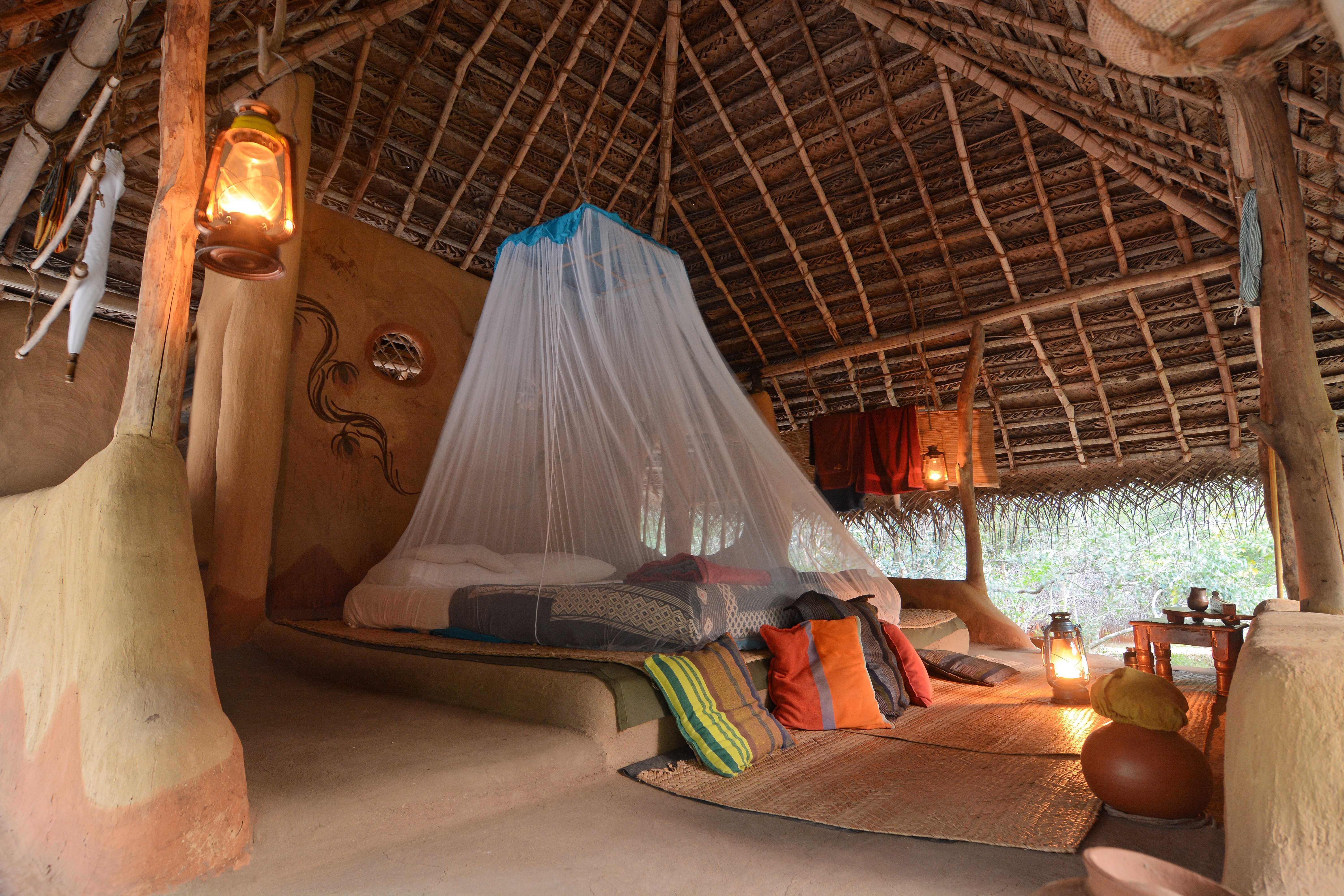 Traditional rustic hut accommodation with thatched roof and colorful furnishings
