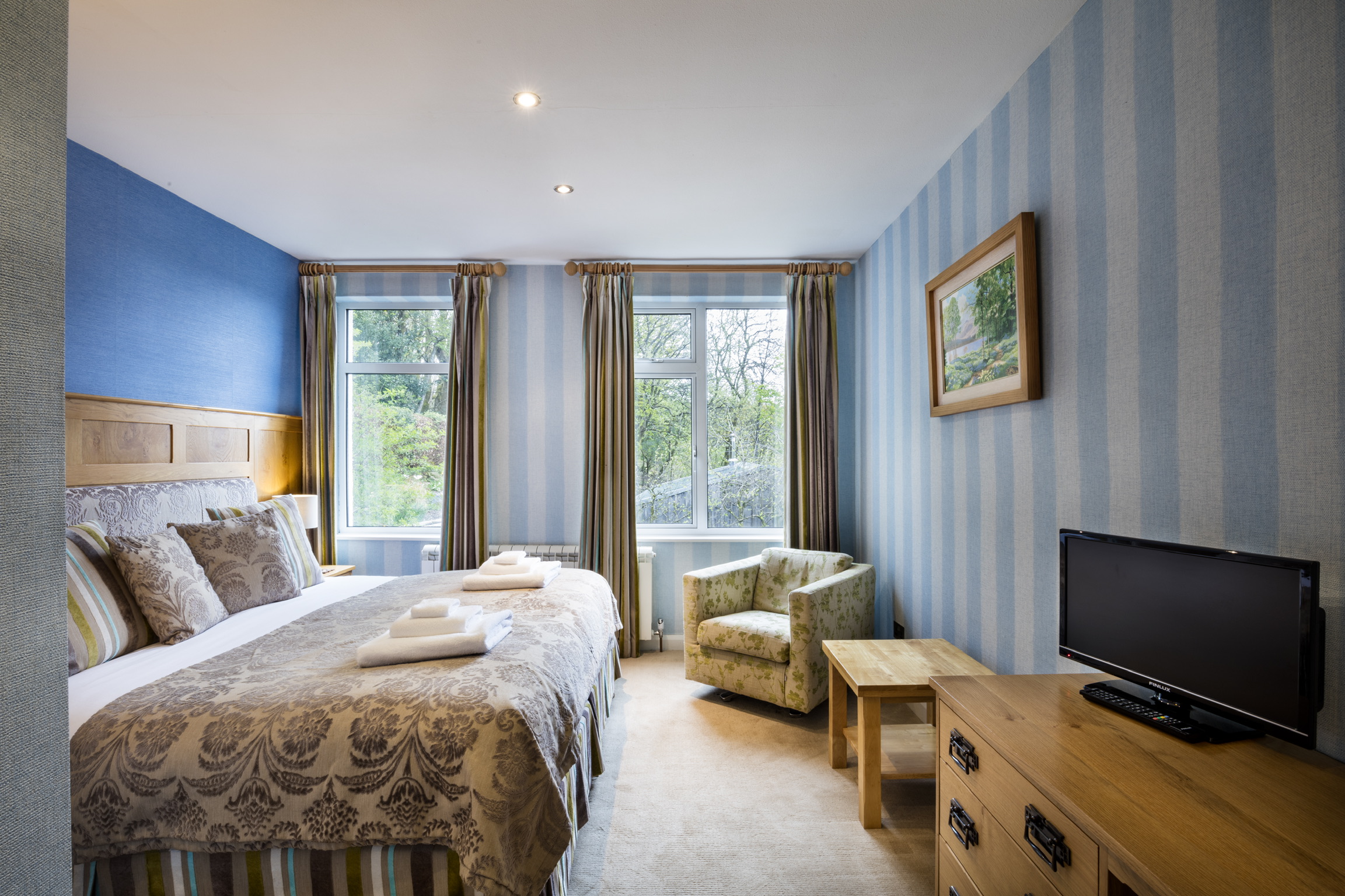 Comfortable guest room at Yewfield with blue striped wallpaper and garden views