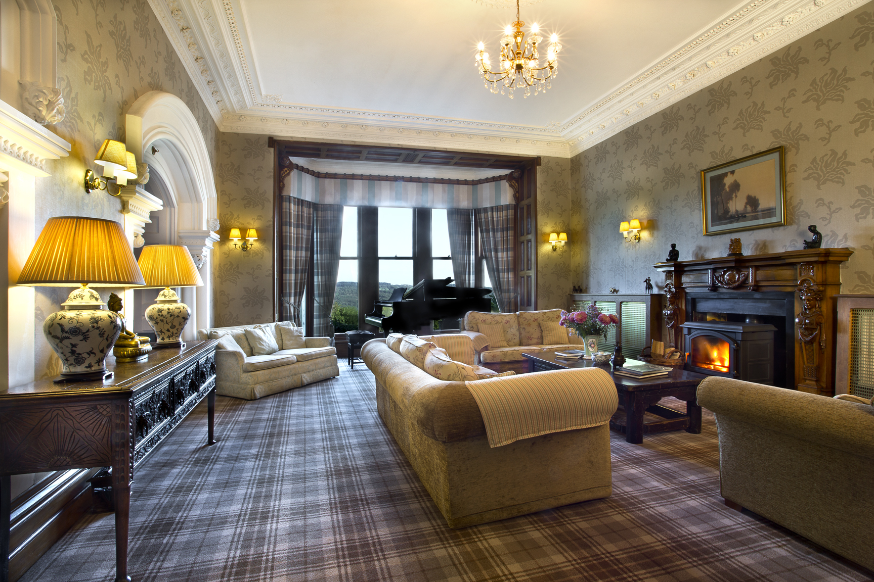 Elegant Victorian lounge at Yewfield with grand piano, crystal chandelier, and mountain views