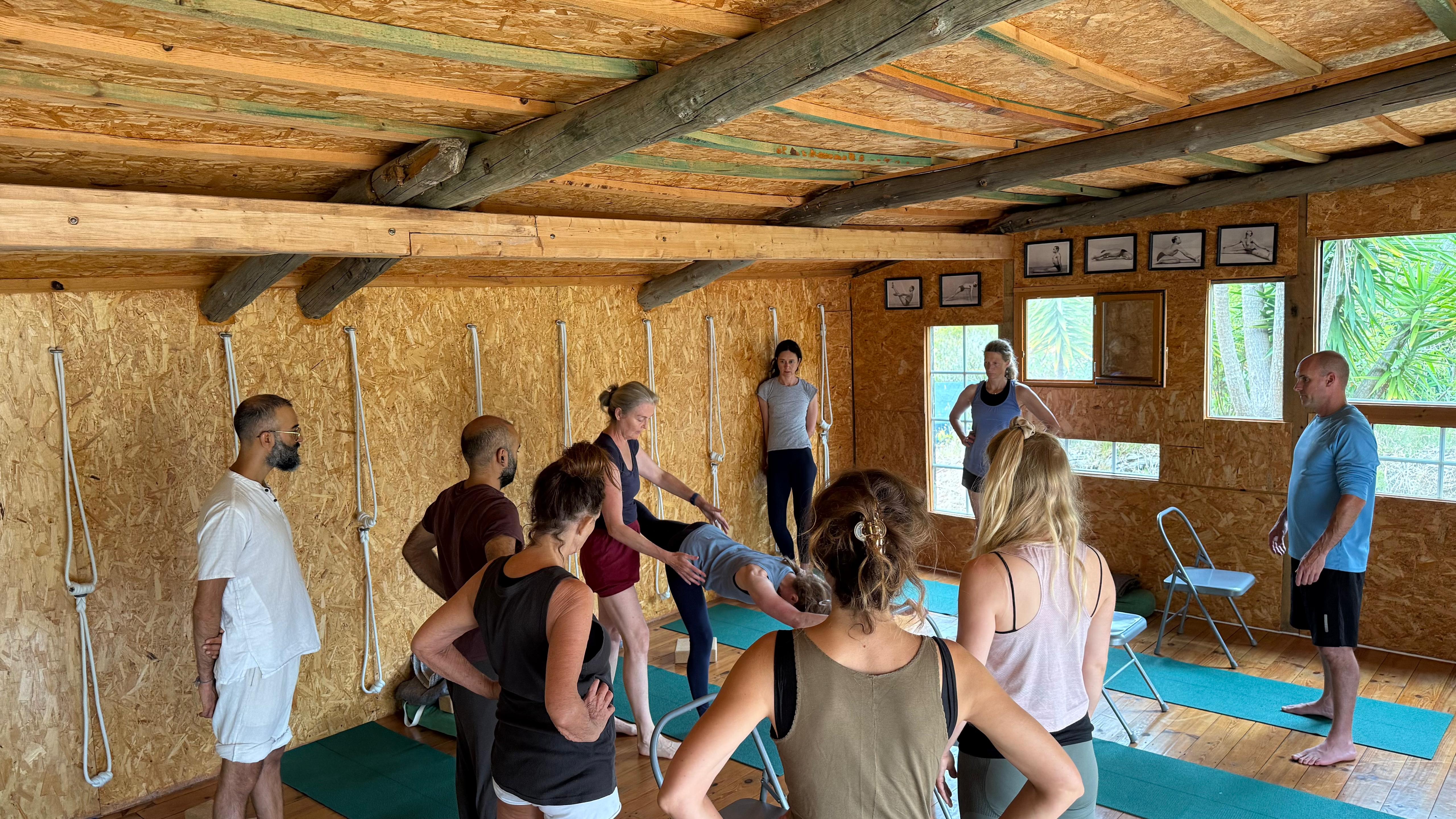 Georgia teaching a yoga class in a wooden studio with students practicing on yoga mats